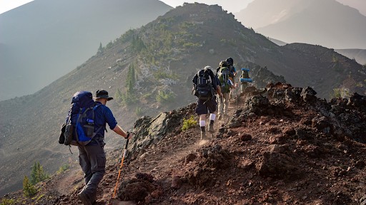individuals engaged in hiking or trekking in a mountainous rugged natural environment